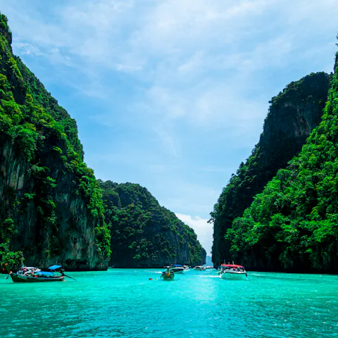 Boats on the sea below a mountain